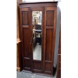 An oak wardrobe with single mirror door and linen fold panels, made by J Tucker and Son,