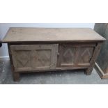 An oak coffer with panelled cupboard doors