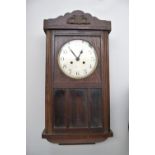 An oak cased wall clock with Arabic numerals, winding key included,