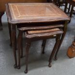 A nest of three tables with tooled and gilt leather tops with glass, on cabriole legs,