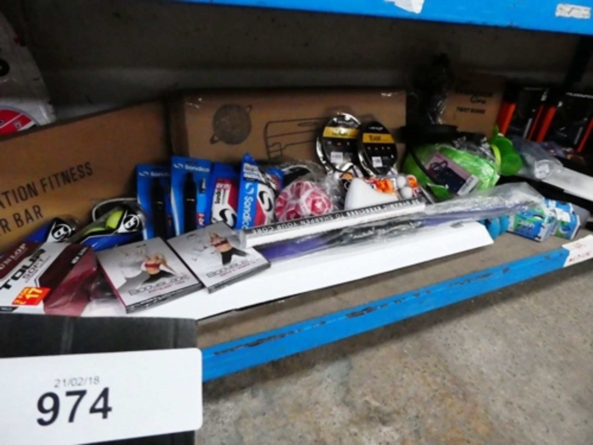 A shelf of sport and fitness equipment including Wonder Core twist board, power bar, golf balls,