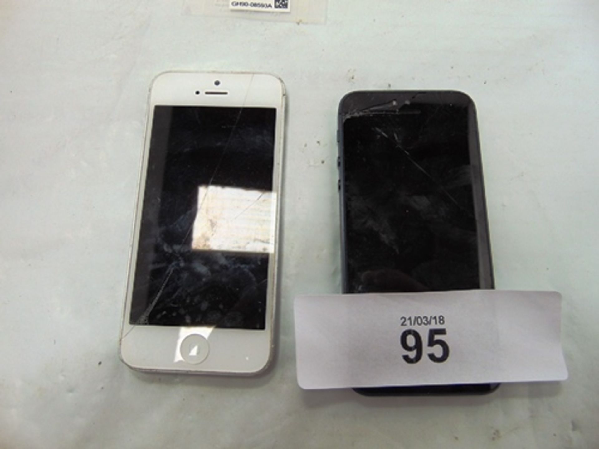 1 x navy and 1 x white Apple iPhone 5's, with damaged screens and back glass, both power on, factory