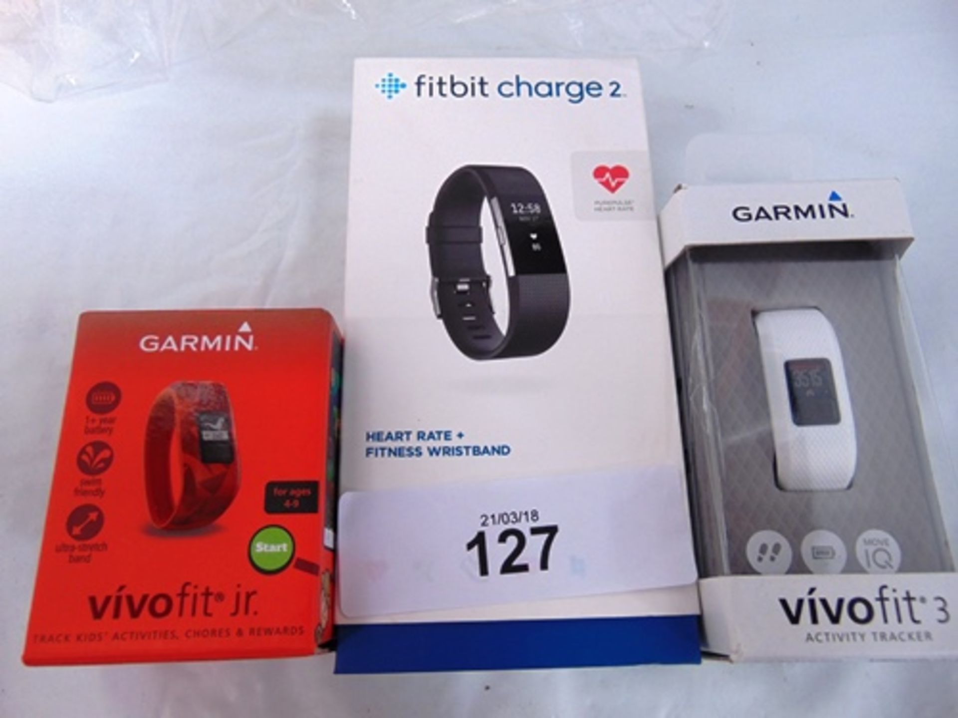 A Garmin Vivo Fit 3, a Vivo Fit Junior, both powered on, together with Fitbit Charge 2, does not