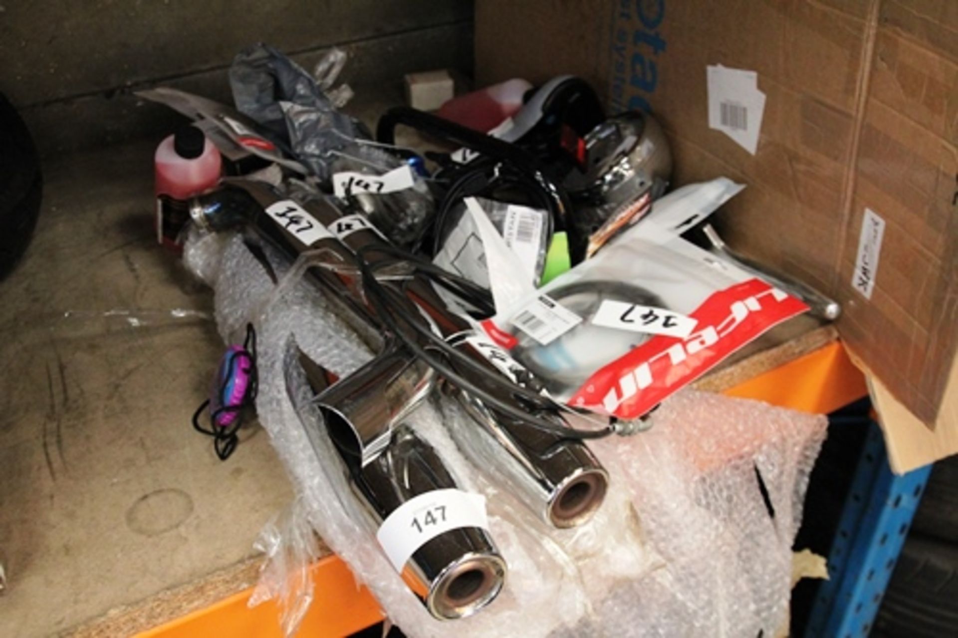 A selection of new and second-hand motorcycle spares including quad carbs, chrome exhaust, handlebar