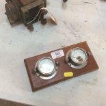 An amp meter and a volt meter set on a wooden plaq