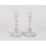 A pair of 19th Century cut glass candlesticks, having faceted baluster columns and circular spread