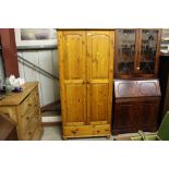 A modern pine wardrobe fitted single drawer below