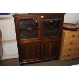 An oak and leaded glass cabinet with linen fold de