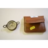 A compass contained in brown leather pouch