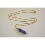 A lapis lazuli pendant hung to a yellow metal chai