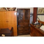 An oak and leaded glazed display cabinet raised on