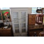 A white painted two door bookcase fitted two drawe