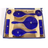 A silver and blue enamel cased dressing table set,