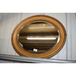 A gilt framed oval and bevel edged mirror