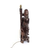 A Chinese carved hardwood lamp base, in the form of an immortal leaning on a staff with attendant