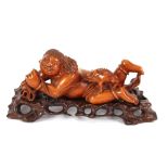A 19th Century Chinese boxwood figure of a recumbent boy, playing with a three legged mystic