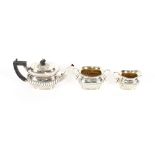 An Edwardian silver three piece bachelor's tea set, of half fluted body design, the teapot with