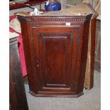 A George III oak hanging corner cupboard, with dentil moulding, fitted with interior shelves