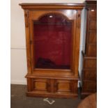 A Victorian golden oak gun cabinet, the upper section enclosed by an arched panel door with