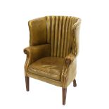 A George III style barrel back armchair, upholstered in green leather, raised on square section