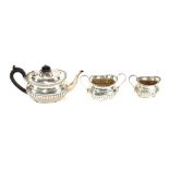 A late Victorian silver bachelor's tea set, of half fluted body form, the teapot with blackwood