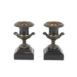 A pair of 19th Century bronze campana shaped urns, raised on black marble plinths, 23cm high