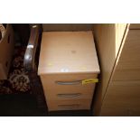 A beech effect bedside chest fitted three drawers
