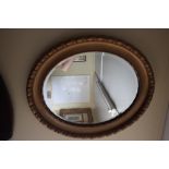 An oval gilt framed bevelled edge wall mirror