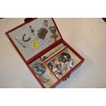 A red leather jewellery box containing silver and