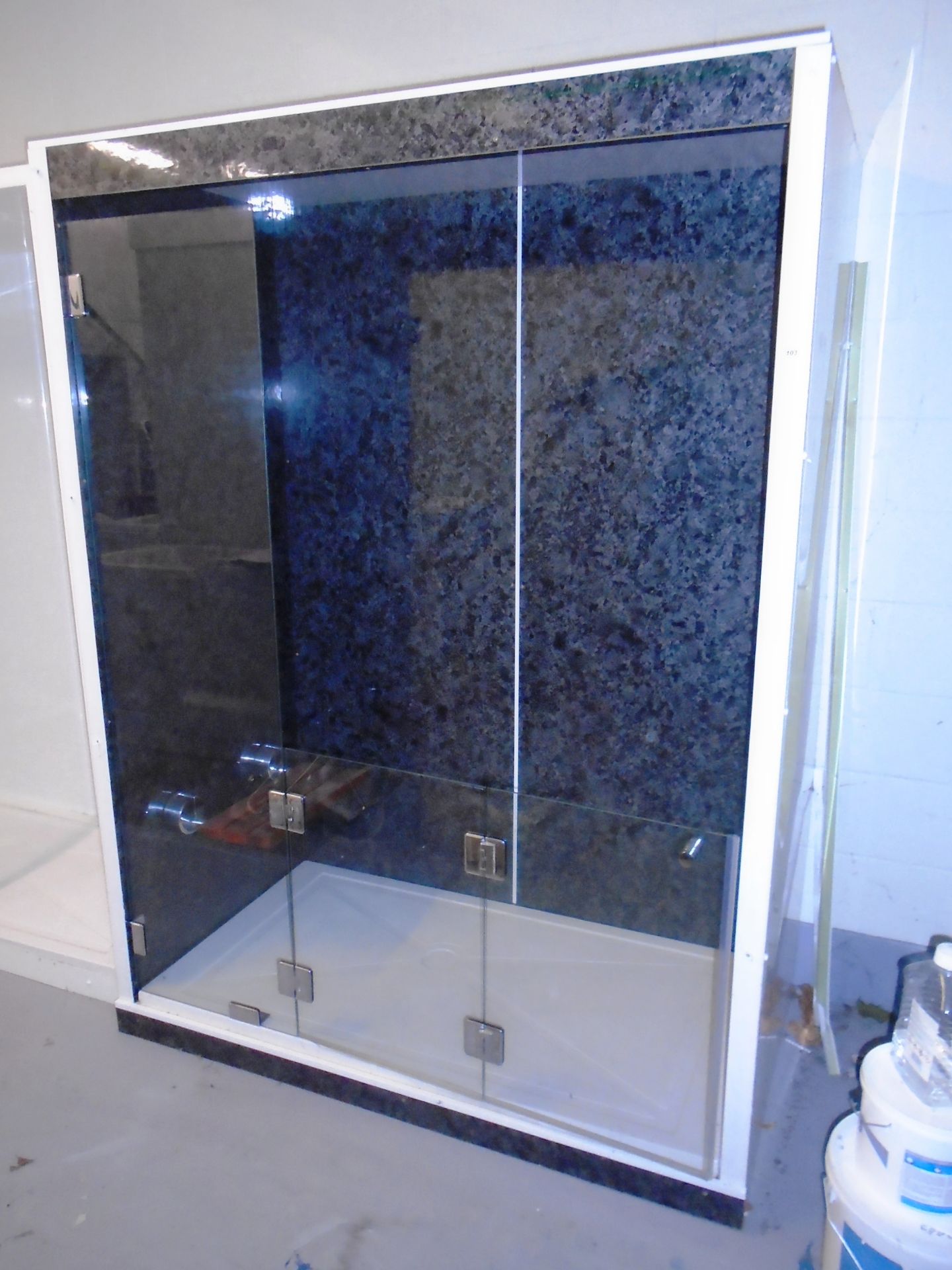 A walk in shower enclosure with black marble effect splash back panels, glass bi-folding door,