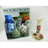 A Moorcroft pottery candlestick in the "Magnolia" pattern on a cream ground [21.