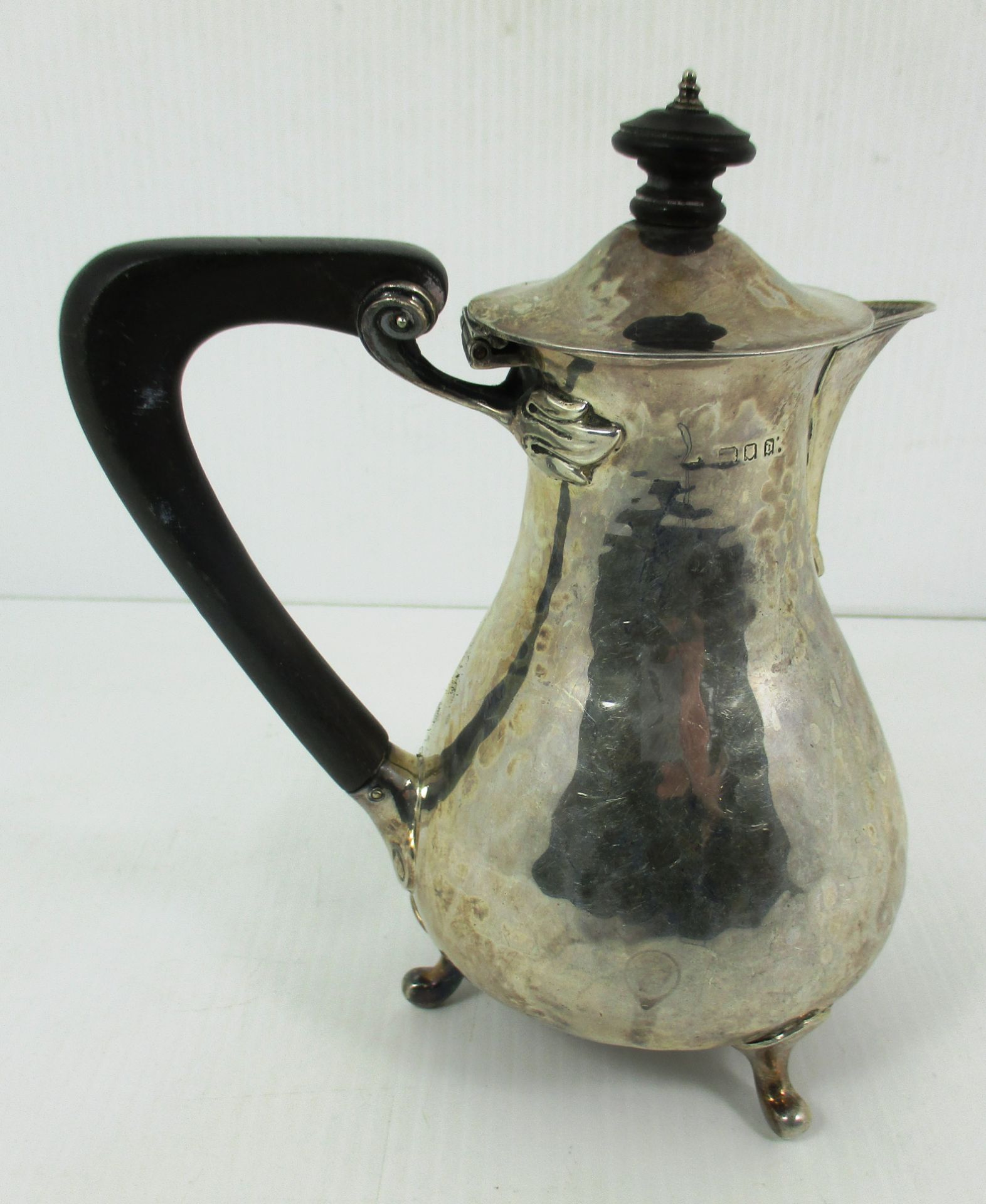 A silver teapot with ebonised loop handle and finial, on three bracket feet,