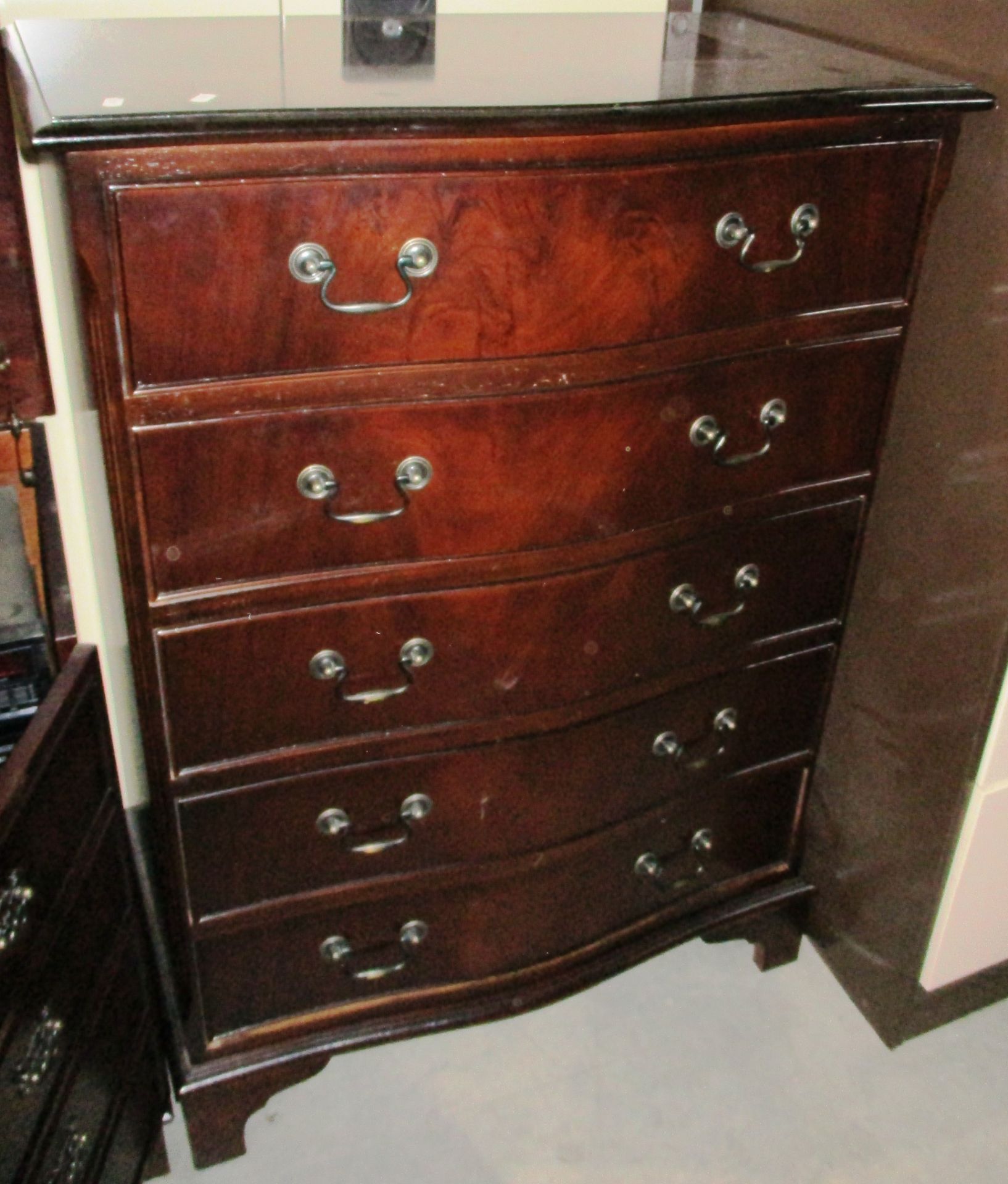 A reproduction mahogany serpentine front 5 drawer chest of drawers