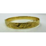 A 9ct gold hinged bangle with engraved decoration (total approx weight 16.