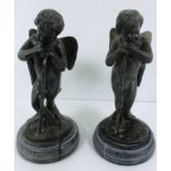 A pair of cast metal cherub figures on faux marble bases - as seen 25cm high