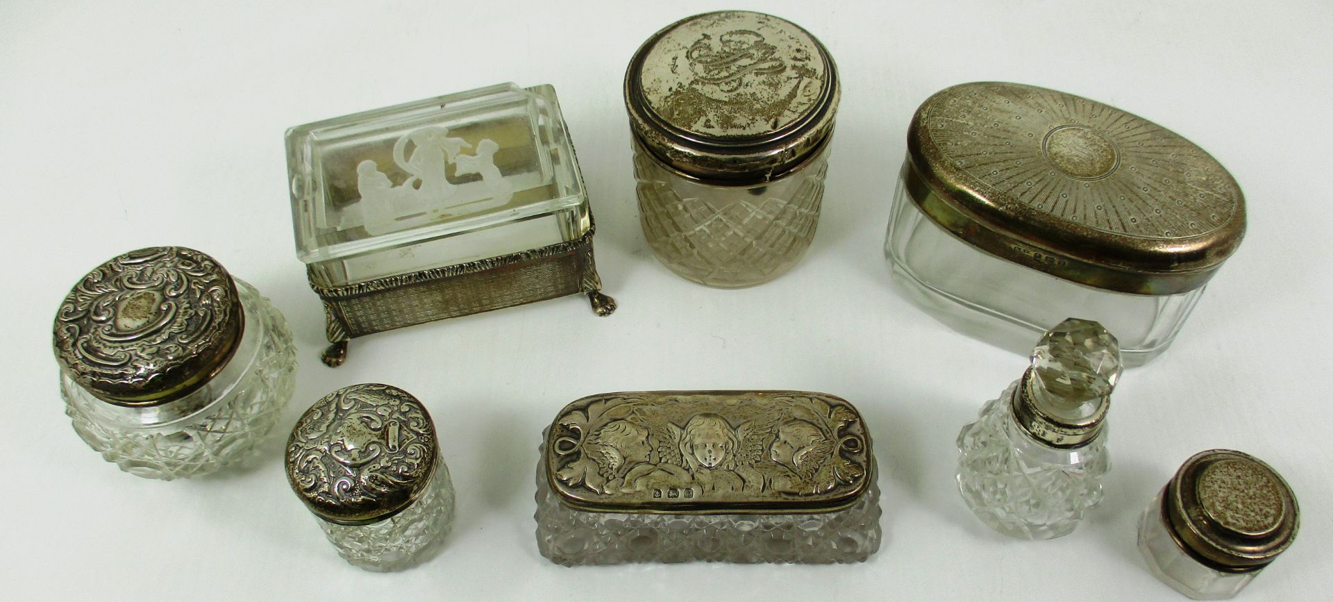 A small cut glass trinket box with silver cover/lid, embossed with cherub design, Birmingham 1906,