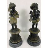 A pair of cast metal cherub figures on faux marble bases