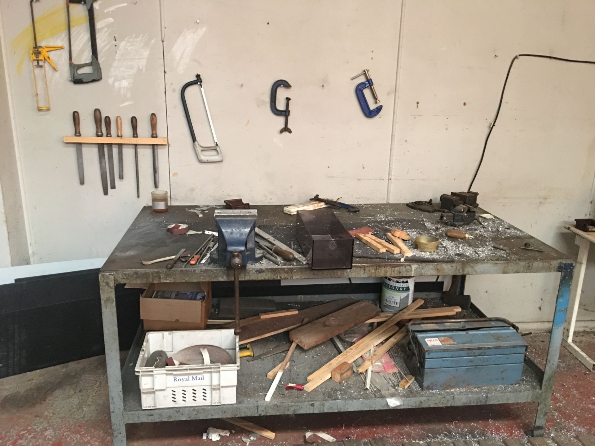 Metal work bench and vice with toolbox and hacksaws and files to wallside