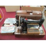A Singer portable sewing machine in an oak finish case complete with two boxes of accessories