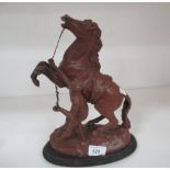 A small metal statue of a man holding a horse 30cm high on a wooden plinth