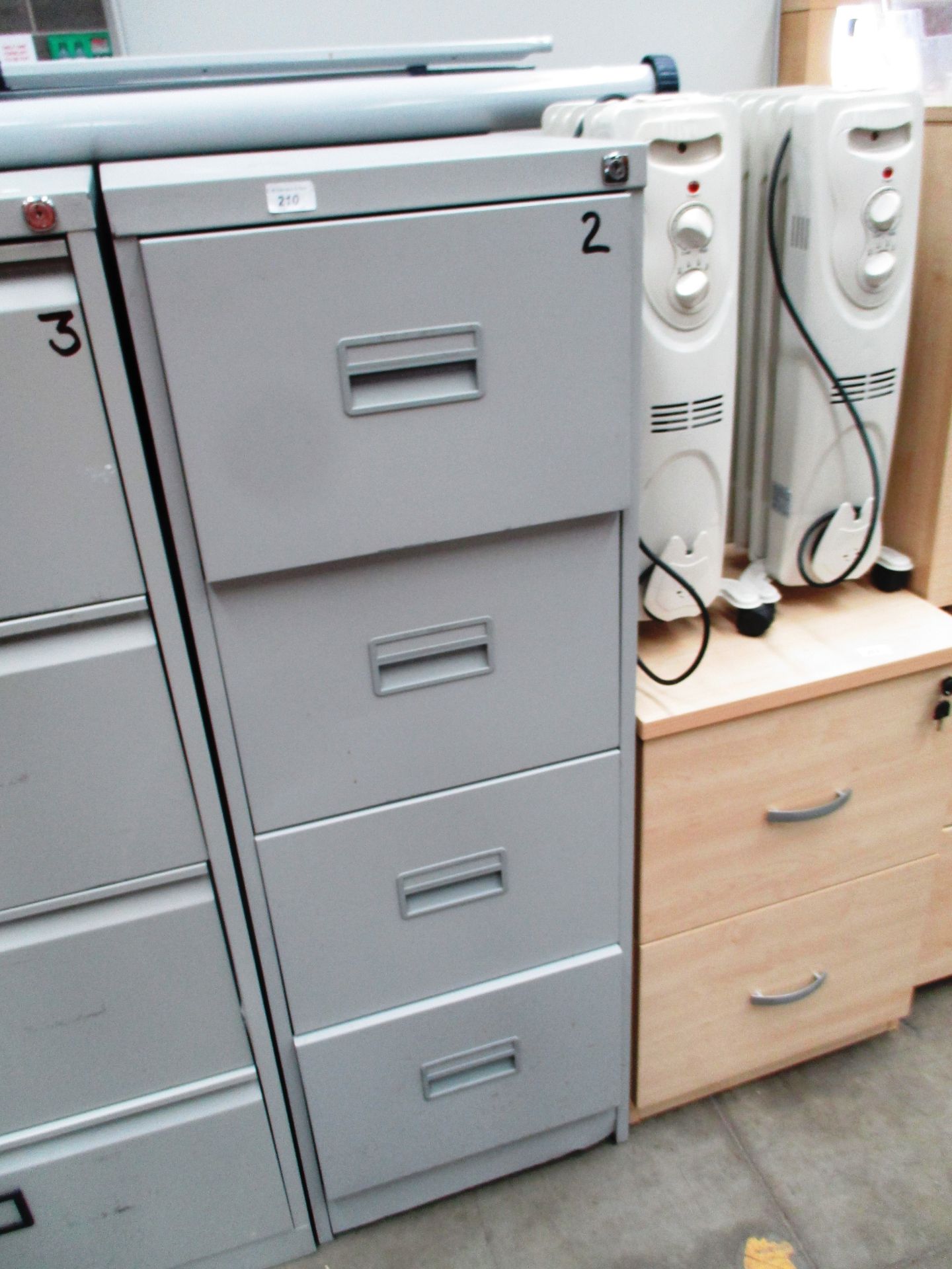 A grey metal four drawer filing cabinet