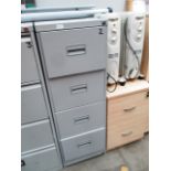 A grey metal four drawer filing cabinet