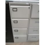 A grey metal four drawer filing cabinet