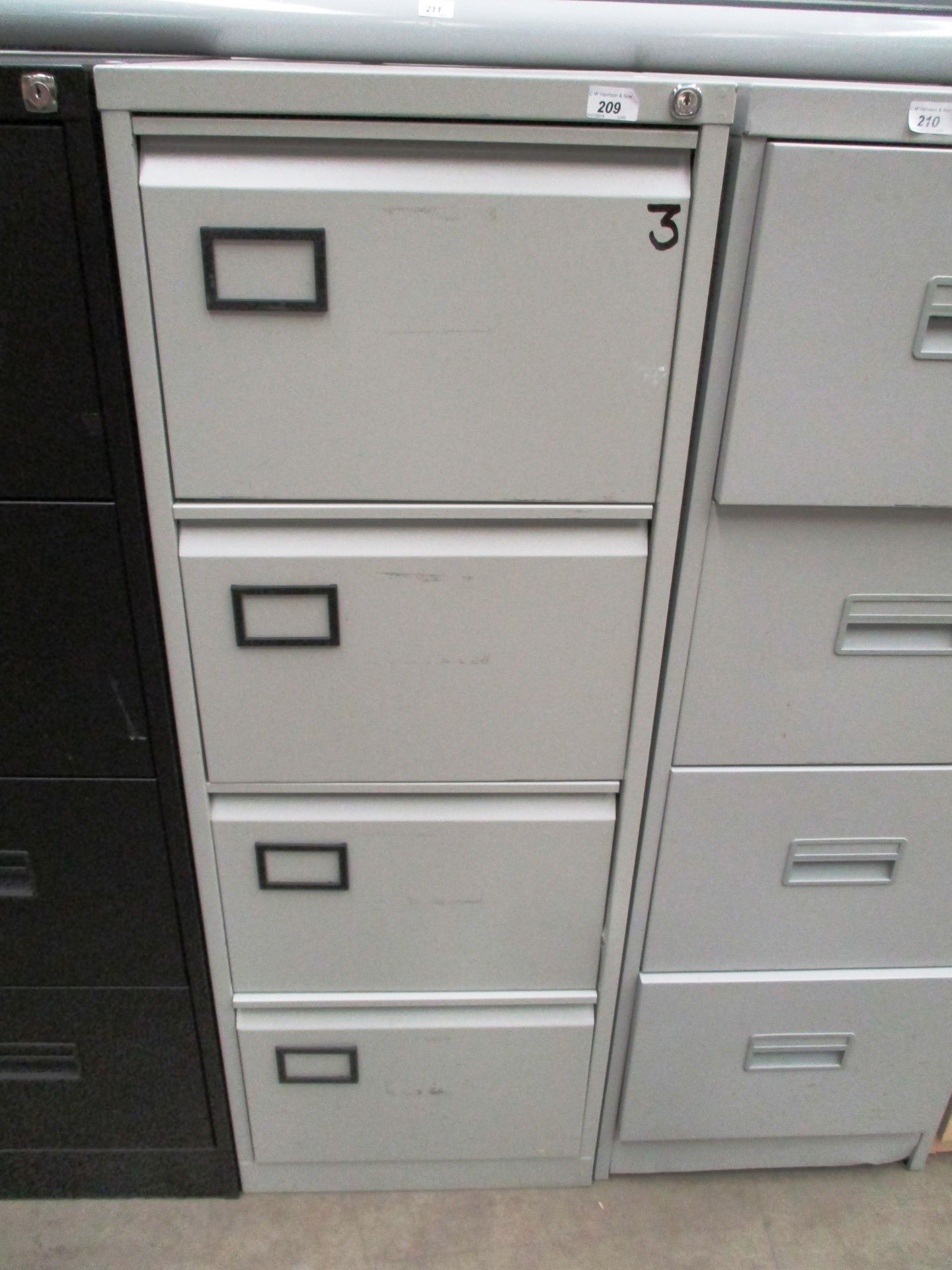 A grey metal four drawer filing cabinet
