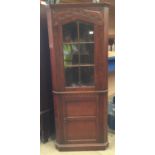 An oak corner cabinet with upper glazed door,