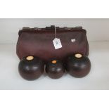 A small brown leather finish bowls bag containing two bowls and a jack by Taylors of Glasgow
