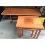A nest of three teak coffee tables together with a larger teak coffee table.