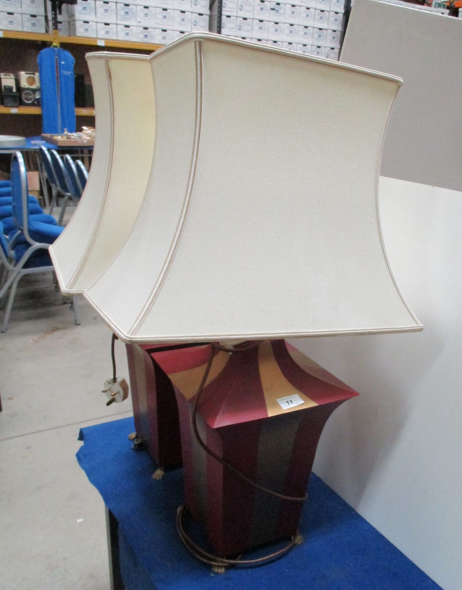 A pair of gold and red painted metal table lamps with cream shades