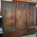 A large Victorian stained mahogany shop display unit with three section glazed sliding doors,