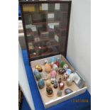 A mahogany finish glass front wall cabinet enclosing a collection of decorative treasury eggs and